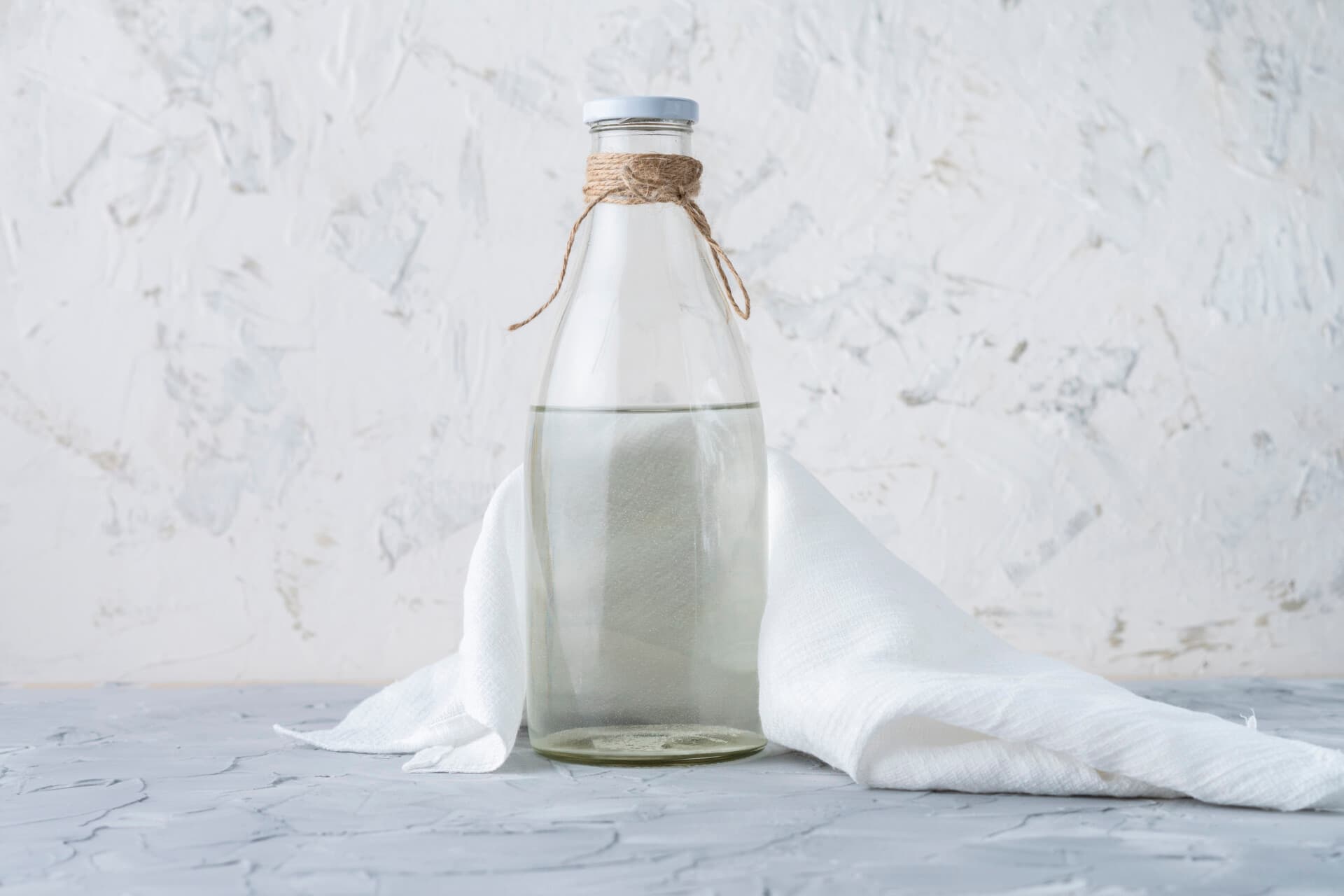 Glazen fles met heldere vloeistof — azijn als huismiddel tegen schimmelnagels